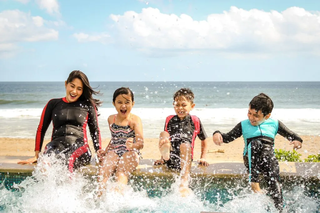 A woman and three children playing in water