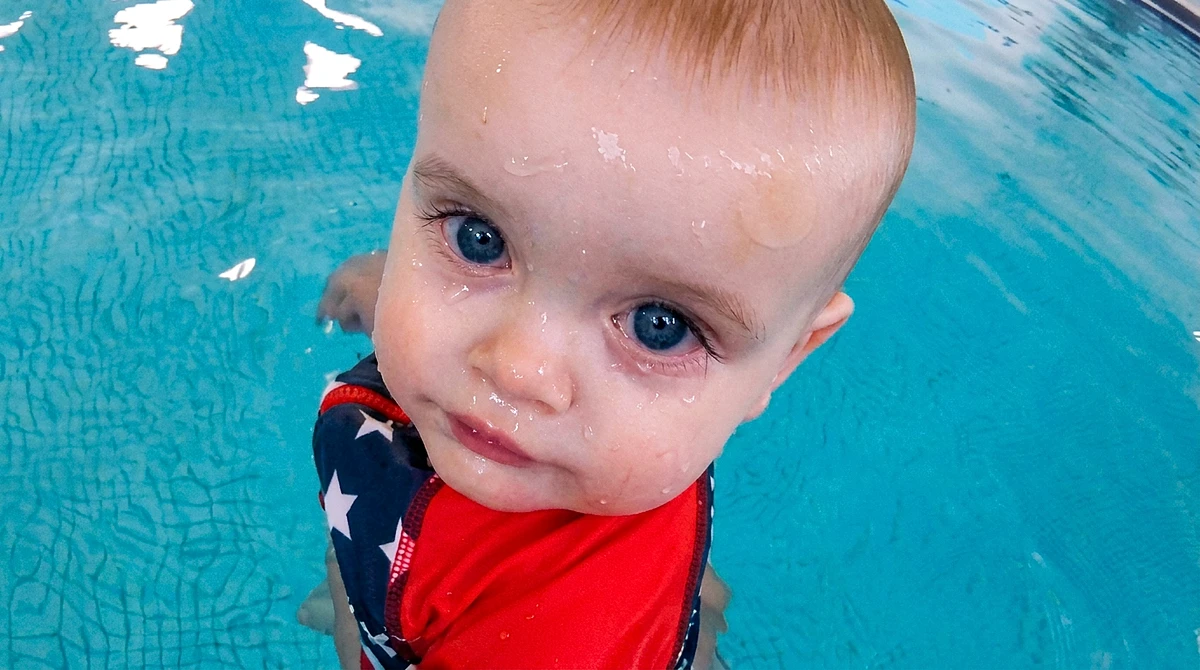A happy baby in the pool, ready to start swim lessons