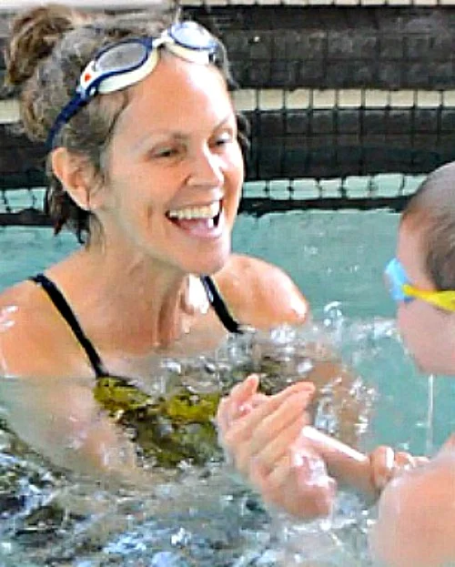 Tessa Rhodes laughing with a young swimmer in the pool